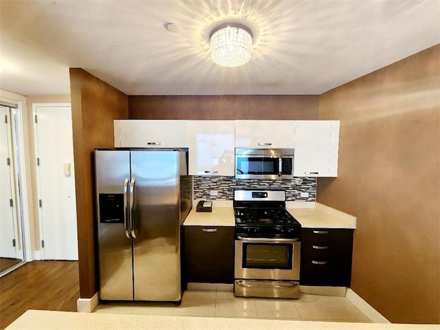 110 Neptune Ave Unit 3H, Brooklyn, NY 11235 - kitchen with stainless steel appliances, light countertops, white cabinets, a chandelier, and baseboards