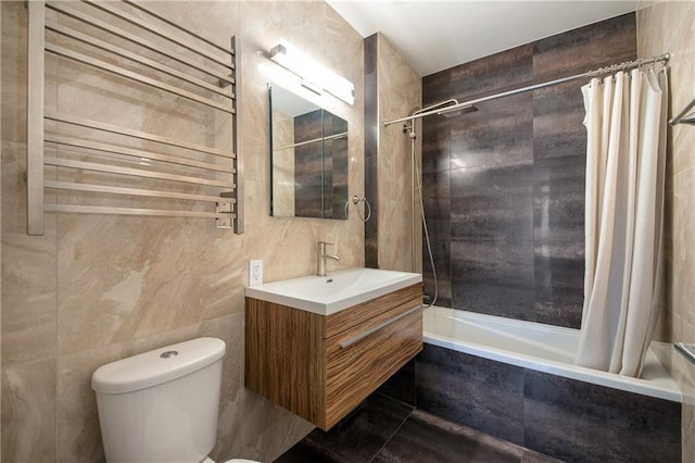 full bath with tile walls, vanity, toilet, radiator heating unit, and tiled shower / bath combo
