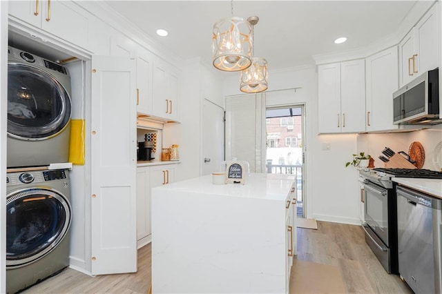 286 Bay 10th St, Brooklyn, NY 11228 - kitchen featuring stainless steel appliances, stacked washer / drying machine, a kitchen island, light wood finished floors, and white cabinetry