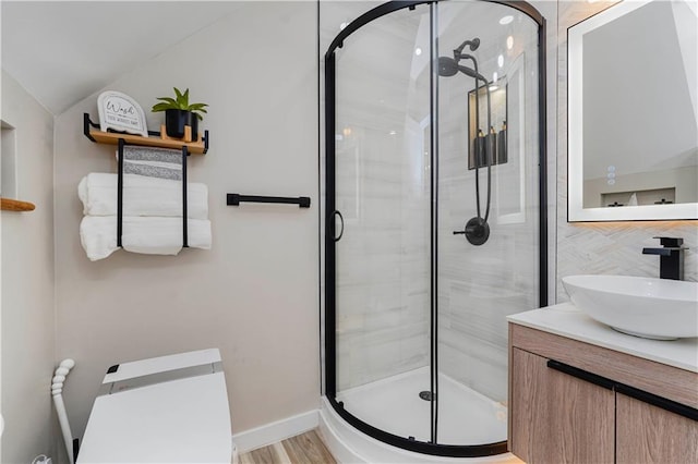 286 Bay 10th St, Brooklyn, NY 11228 - bathroom featuring a stall shower, lofted ceiling, vanity, wood finished floors, and baseboards