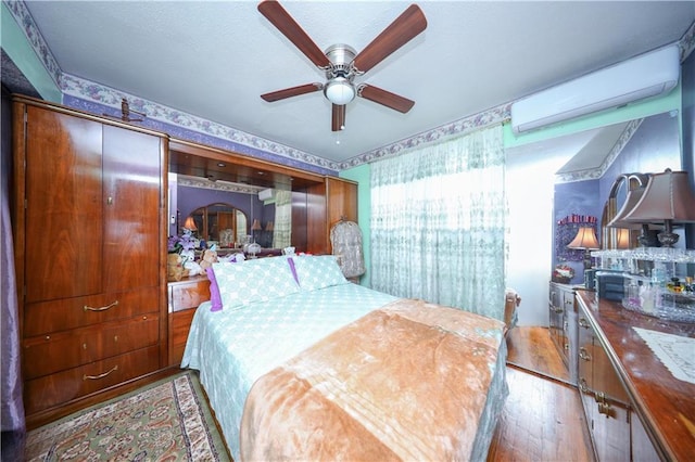bedroom featuring a ceiling fan, a wall mounted AC, and hardwood / wood-style floors