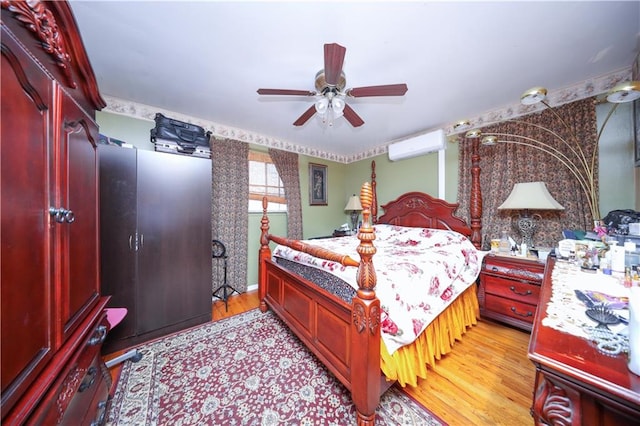 bedroom featuring ceiling fan, an AC wall unit, and light wood-style flooring