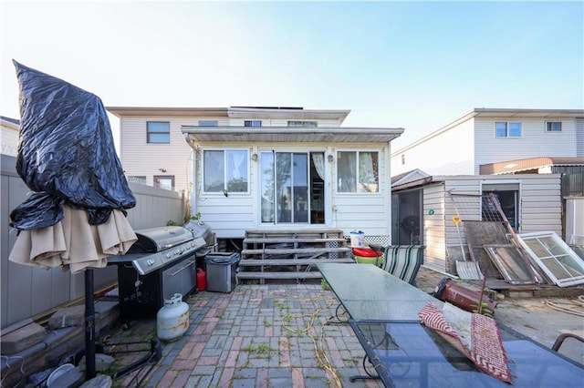 rear view of property featuring fence, a storage unit, an outdoor structure, entry steps, and a patio