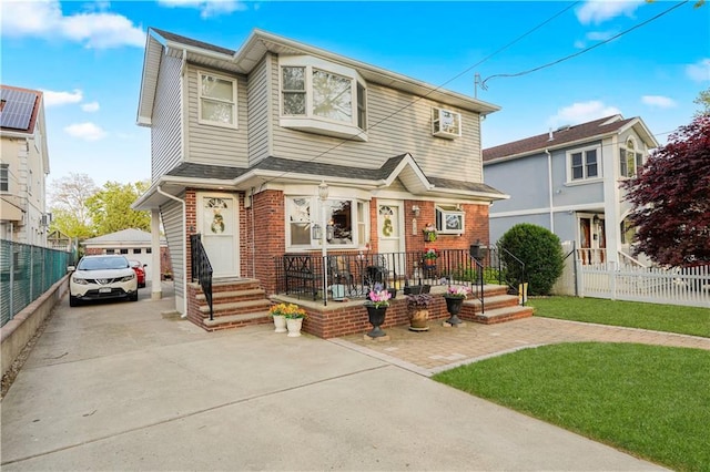 view of front facade featuring a detached garage, brick siding, and fence