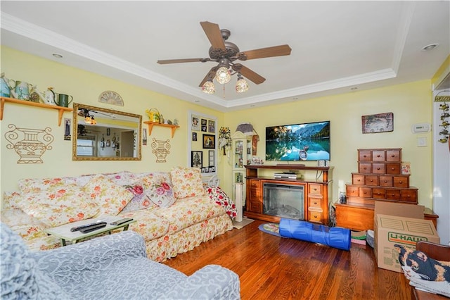 living room featuring crown molding, ceiling fan, a tray ceiling, and wood finished floors