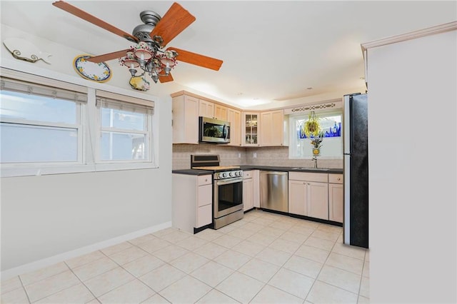 kitchen featuring ceiling fan, decorative backsplash, dark countertops, appliances with stainless steel finishes, and a sink