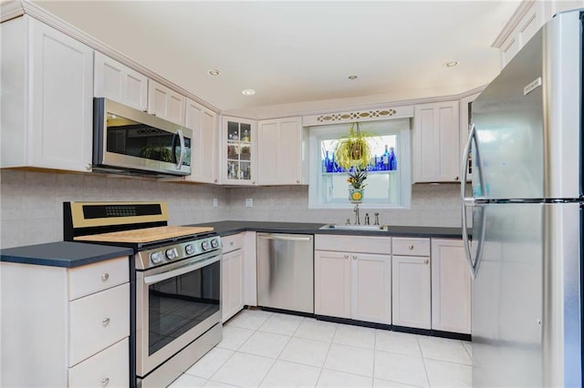 kitchen with stainless steel appliances, dark countertops, decorative backsplash, and a sink