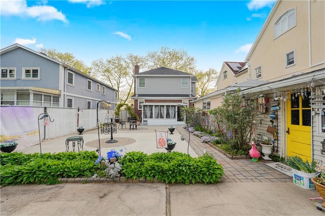 rear view of house featuring fence, a sunroom, a patio area, and a residential view