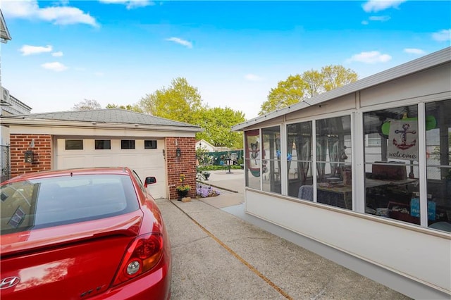 view of home's exterior with a detached garage, a sunroom, and brick siding