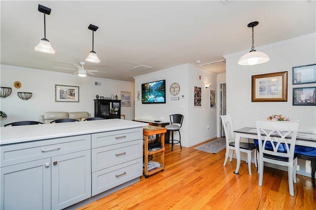 kitchen featuring crown molding, hanging light fixtures, a ceiling fan, and light wood finished floors