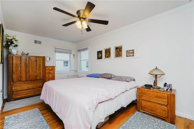 bedroom featuring visible vents, ornamental molding, ceiling fan, and wood finished floors