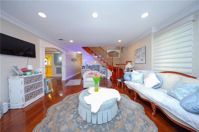 living area with stairs, arched walkways, visible vents, and ornamental molding
