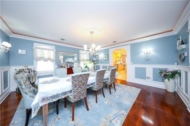 dining area with visible vents, arched walkways, wainscoting, a chandelier, and ornamental molding