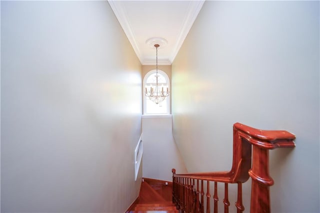 staircase with crown molding and an inviting chandelier