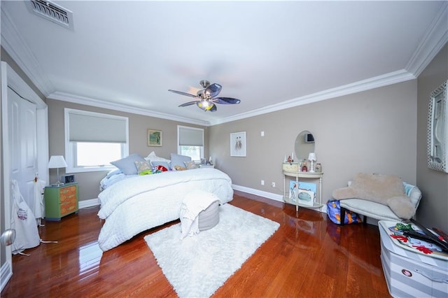 bedroom featuring a ceiling fan, visible vents, wood finished floors, baseboards, and ornamental molding