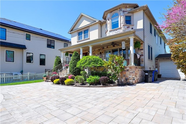 view of front of house featuring covered porch, fence, an attached garage, stairs, and stone siding