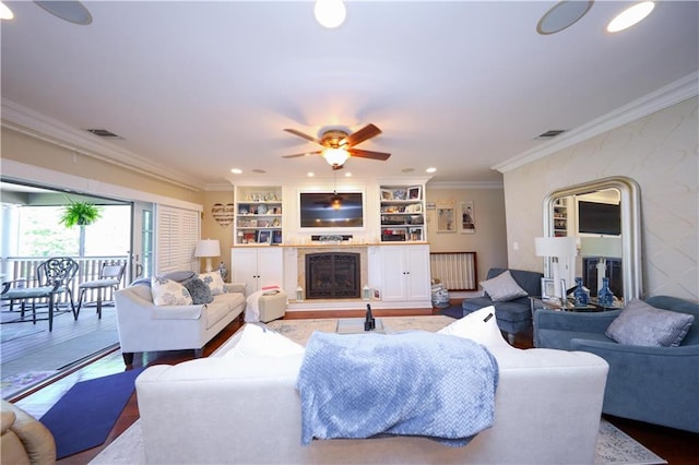 living area featuring crown molding, visible vents, ceiling fan, recessed lighting, and a fireplace with raised hearth