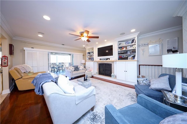 living room featuring ceiling fan, a fireplace with raised hearth, ornamental molding, recessed lighting, and dark wood-style floors