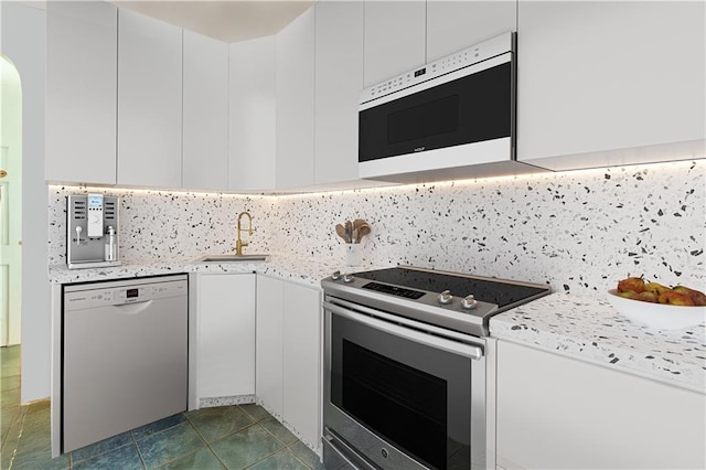 kitchen featuring white microwave, white cabinets, a sink, dishwasher, and stainless steel electric range oven