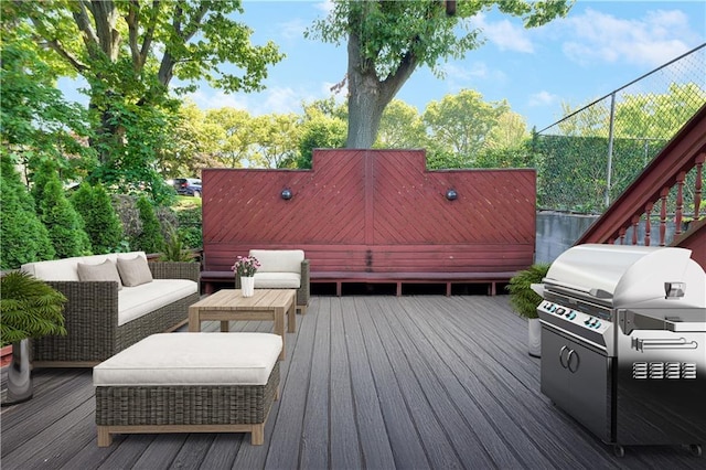 wooden terrace with outdoor lounge area, fence, and grilling area