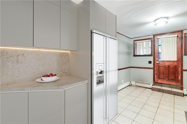 clothes washing area with light tile patterned floors and baseboard heating