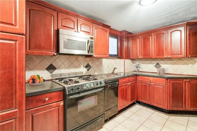 kitchen with reddish brown cabinets, stainless steel microwave, a sink, dishwasher, and gas stove