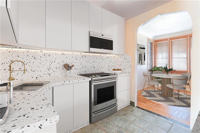 kitchen featuring a sink, white cabinets, tasteful backsplash, and stainless steel range with electric stovetop