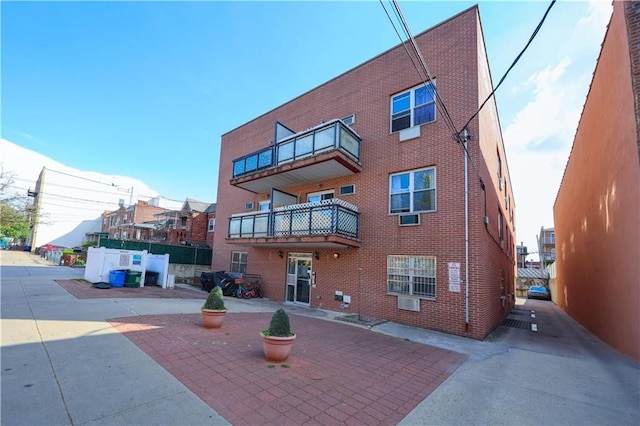 rear view of house featuring brick siding and a balcony