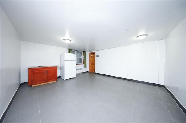 bonus room with dark tile patterned flooring, radiator, and baseboards