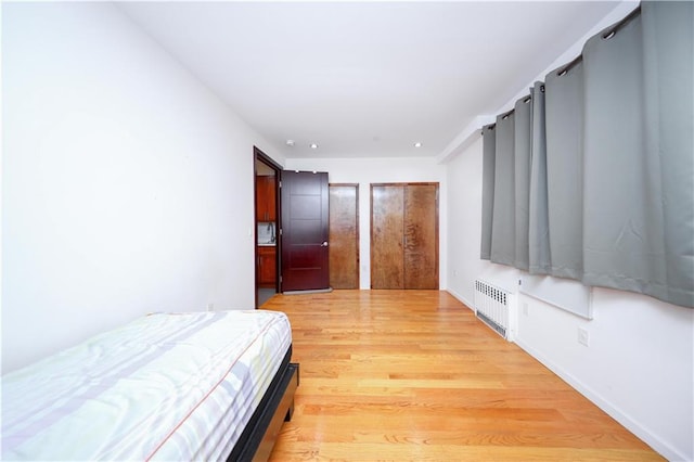 bedroom with light wood-style floors, recessed lighting, and radiator heating unit