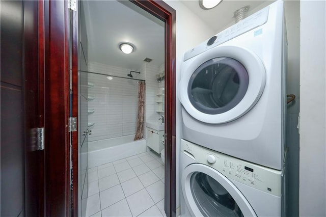 clothes washing area with laundry area, stacked washing maching and dryer, and light tile patterned floors