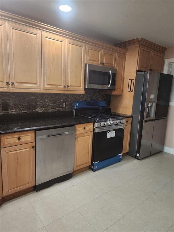 kitchen with baseboards, dark stone counters, tasteful backsplash, and stainless steel appliances