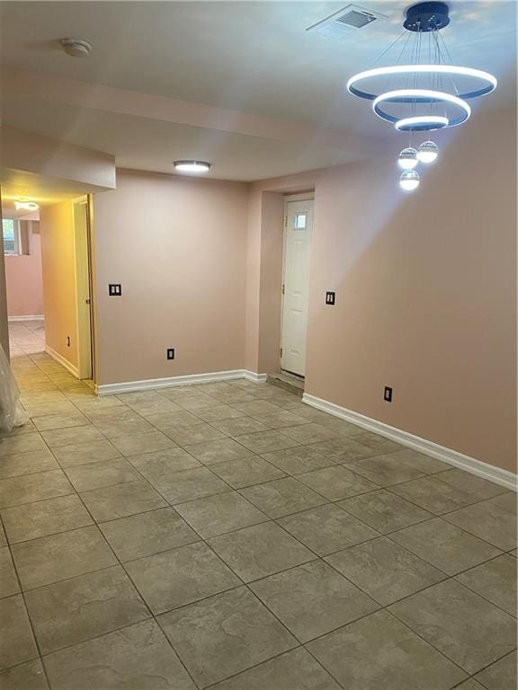 finished below grade area with light tile patterned flooring, baseboards, and visible vents