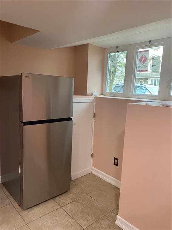 kitchen featuring baseboards, freestanding refrigerator, and light tile patterned flooring