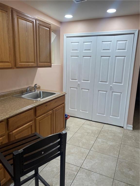 kitchen with brown cabinets, light tile patterned floors, recessed lighting, and a sink