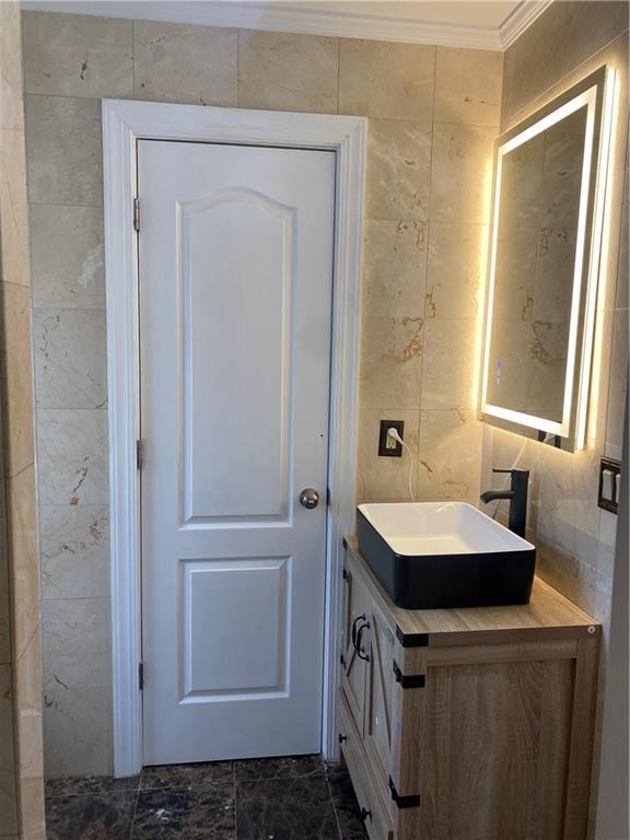 bathroom featuring vanity, ornamental molding, and tile walls