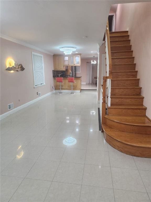 staircase featuring crown molding, baseboards, visible vents, and tile patterned flooring