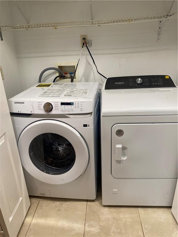 laundry room with laundry area, washing machine and dryer, and light tile patterned flooring