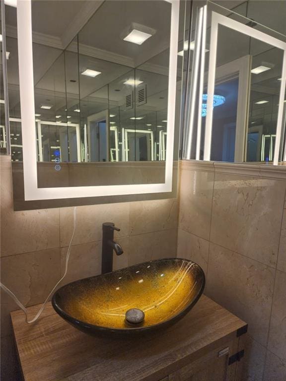 bathroom featuring a sink, tile walls, and ornamental molding