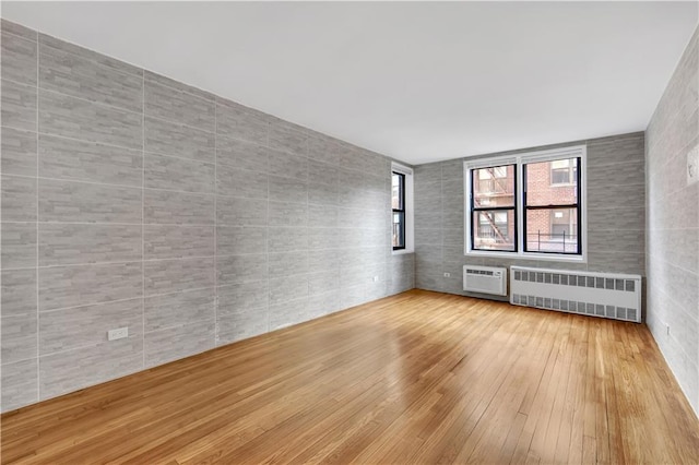 345 Webster Ave Unit 3N, Brooklyn, NY 11230 - unfurnished room featuring radiator, tile walls, wood-type flooring, and a wall mounted AC