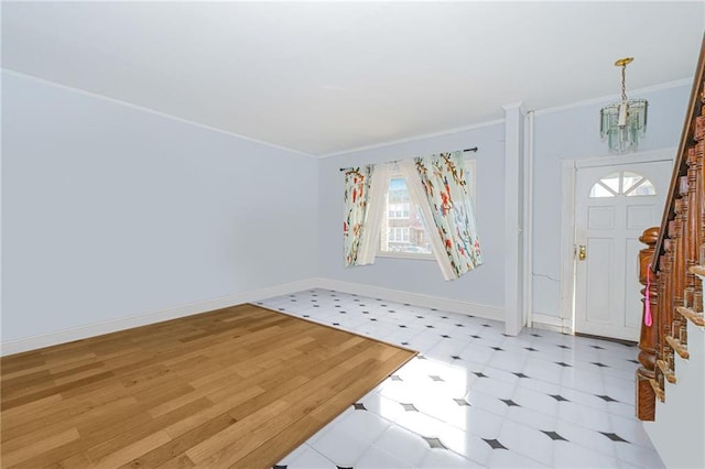 foyer entrance featuring an inviting chandelier, light floors, ornamental molding, and baseboards
