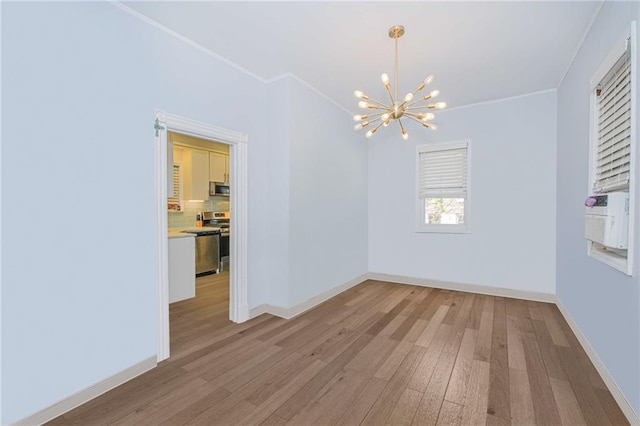 unfurnished dining area with baseboards, a notable chandelier, ornamental molding, and light wood finished floors