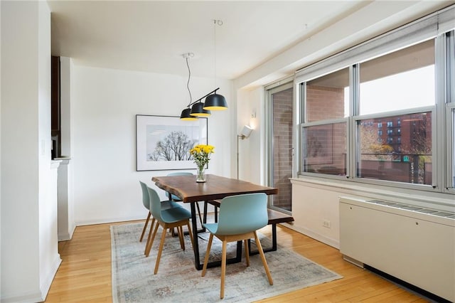 dining space with baseboards, radiator heating unit, and light wood finished floors
