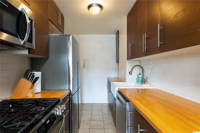kitchen with a sink, wood counters, tasteful backsplash, and stainless steel appliances