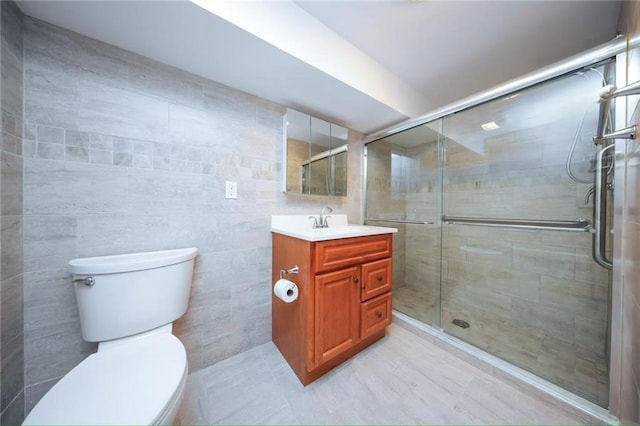 full bath with tile walls, a stall shower, vanity, and toilet