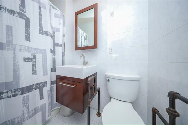 full bath with toilet, tile patterned floors, tile walls, and vanity