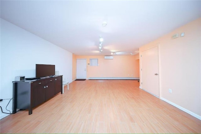 basement featuring an AC wall unit, baseboards, and light wood finished floors