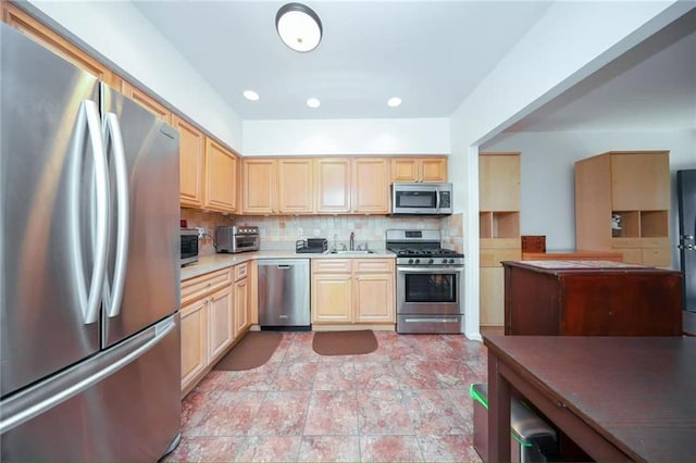 kitchen featuring backsplash, stainless steel appliances, light brown cabinetry, and a sink