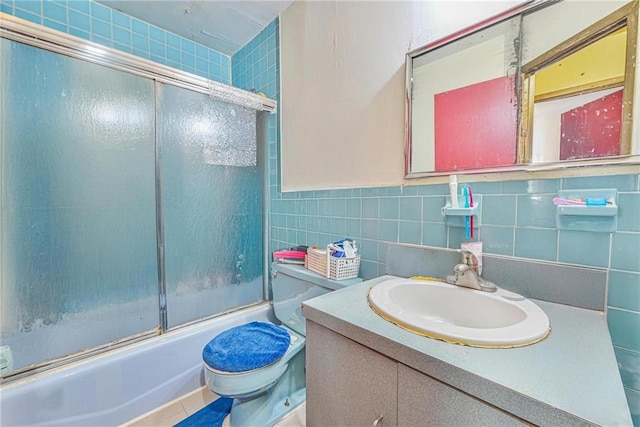 bathroom with tile walls, enclosed tub / shower combo, toilet, and vanity