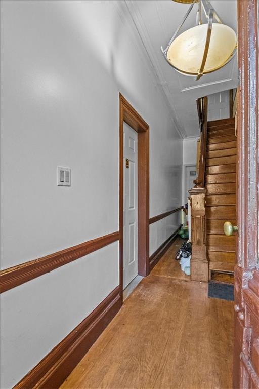 hall featuring crown molding, baseboards, and wood finished floors